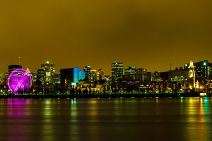 Longue exposition du Vieux-Montréal de nuit, prise à partir de l'île Sainte-Hélène. On reconnait la grande roue, l'horloge du quai, le Marché Bonsecours et les tours du centre-ville de Montréal.